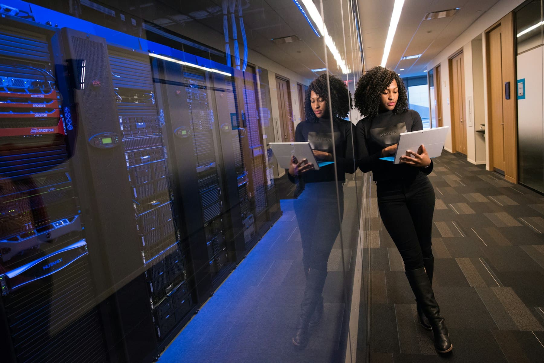 An engineer with a laptop in a data centre corridor, the compute side of an AI model lab for colleges