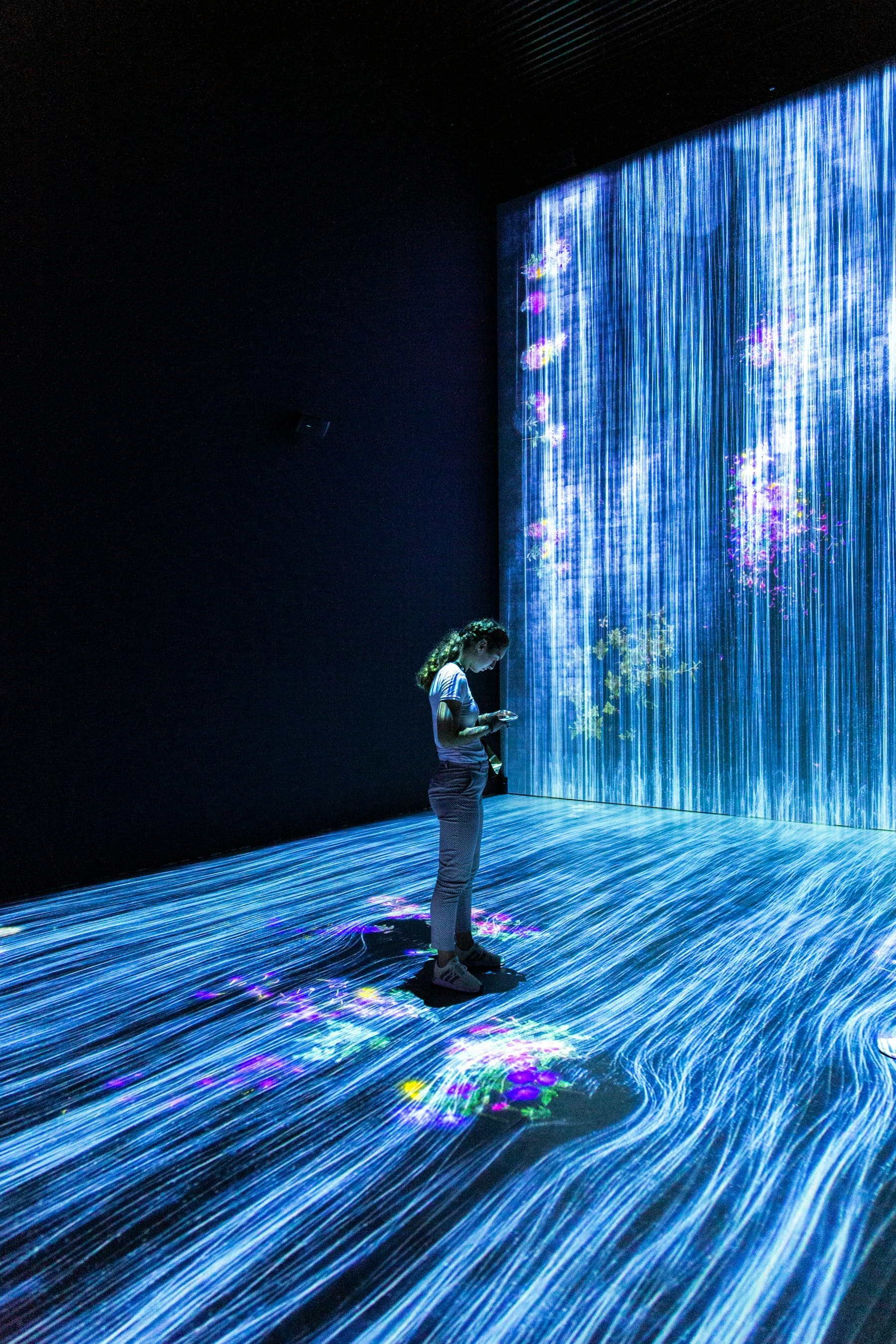 A person standing inside an immersive digital light installation, the creative edge of a generative AI lab for colleges