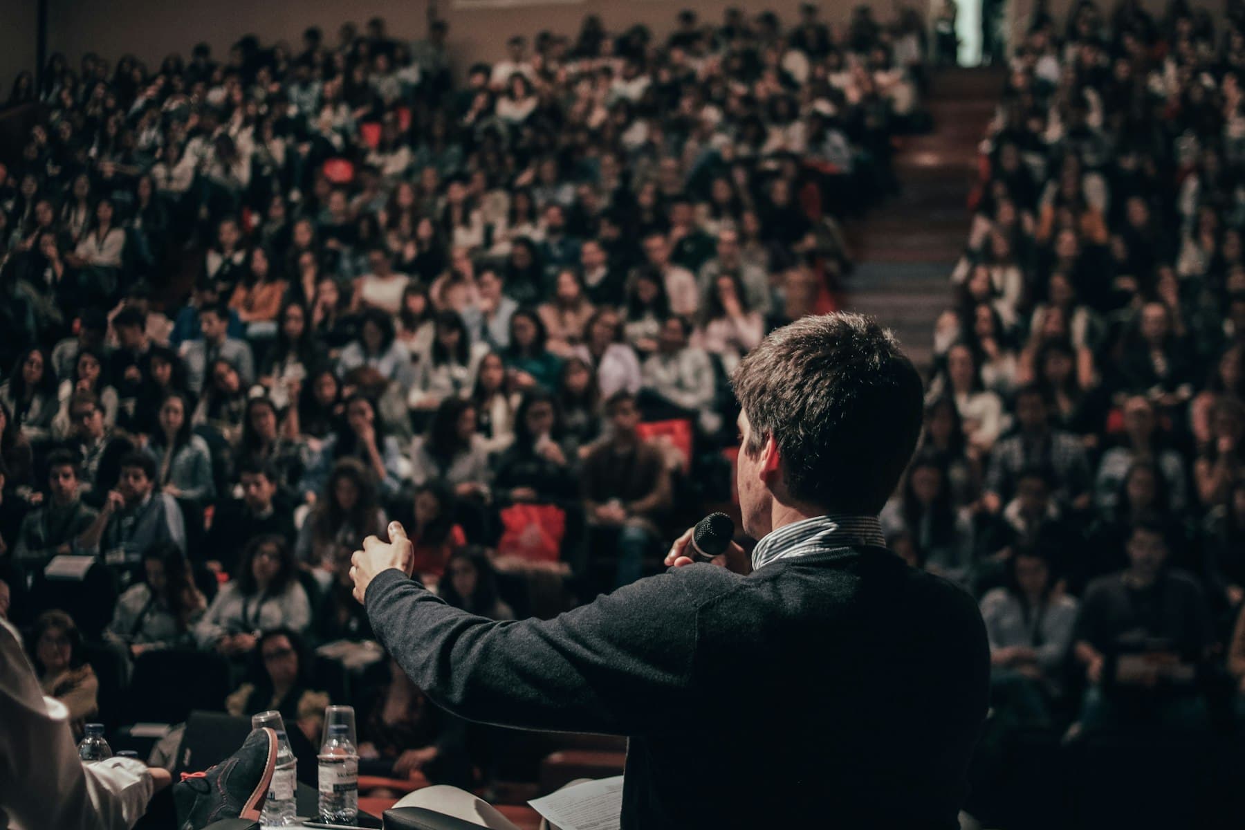 A speaker addressing a packed lecture hall, the kind of room planned for the Inevitable Summit 2027