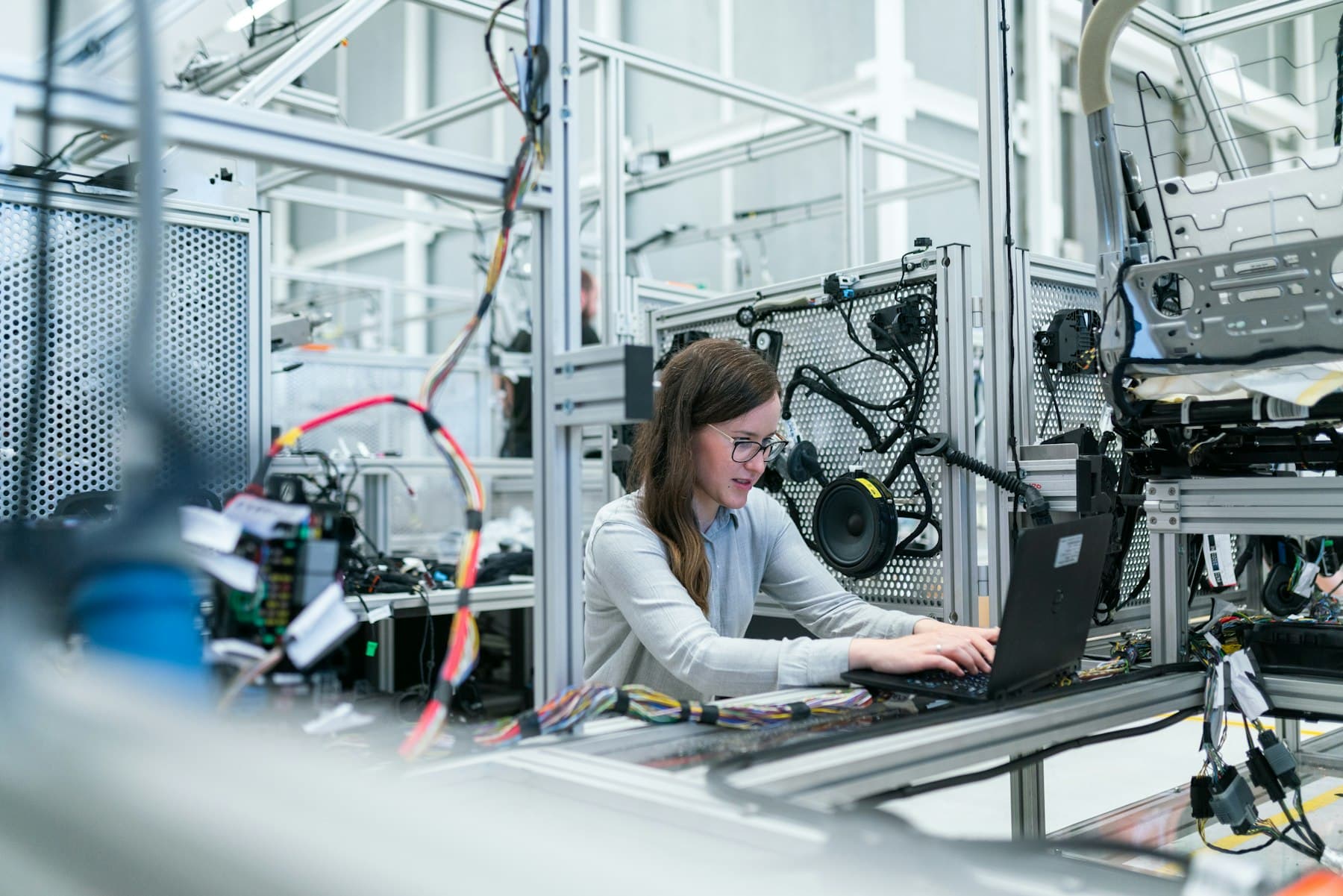 An engineer working on a laptop inside a robotics workcell, as in a robotics lab for engineering colleges