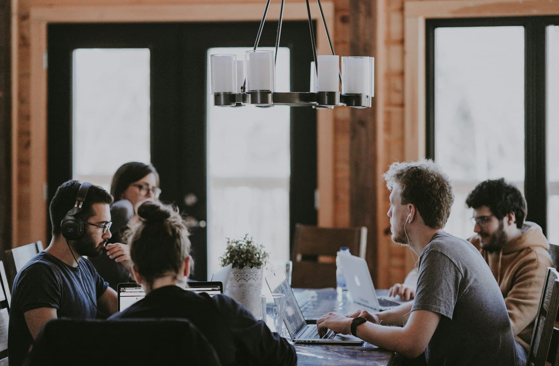 A team meeting around a table with laptops, the setting for an AI upskilling programme for companies