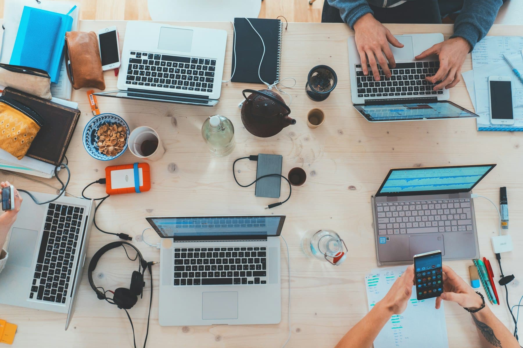Overhead view of hands working at laptops around a shared project table