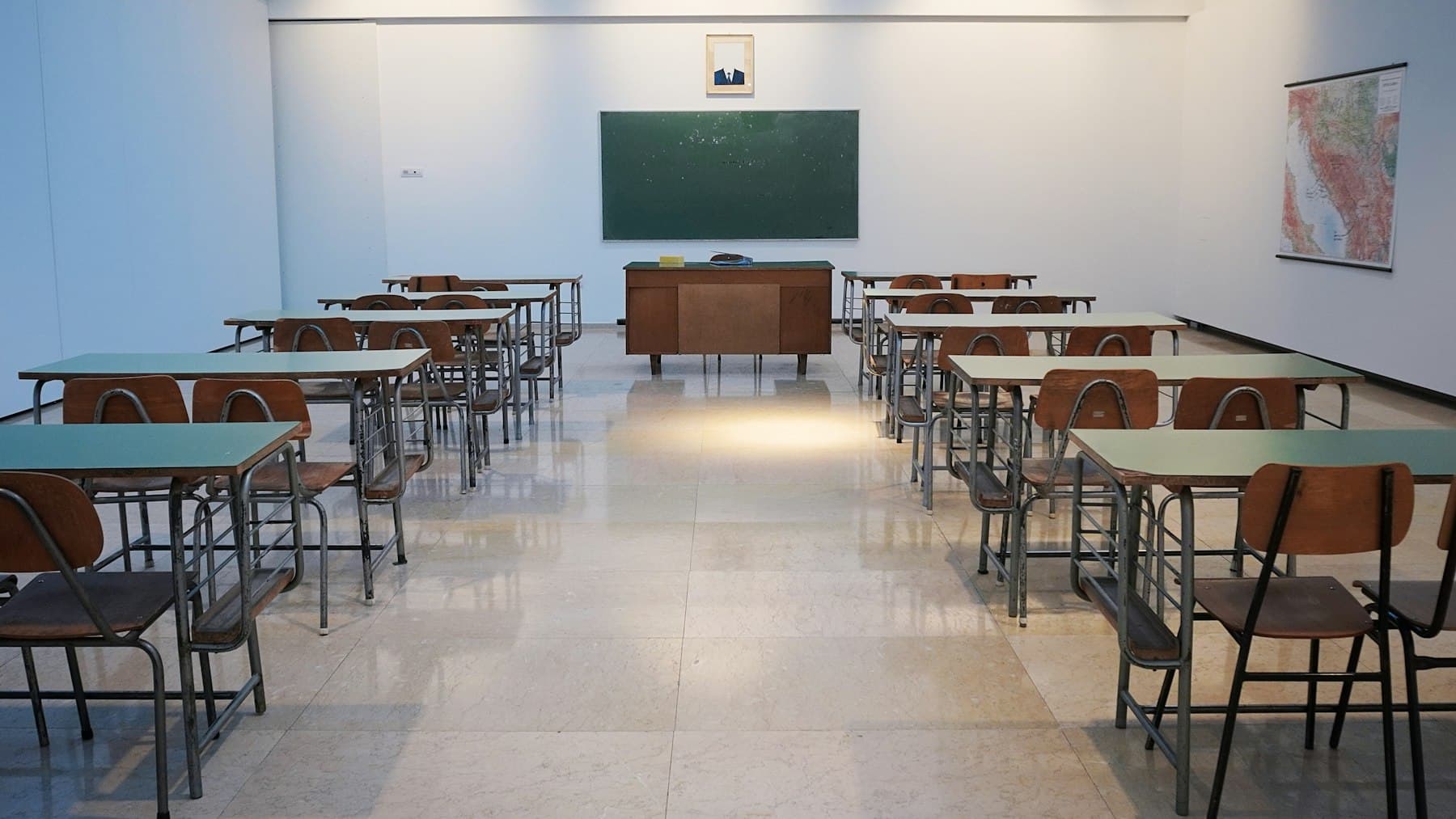 Bright, empty school classroom with rows of desks and a chalkboard