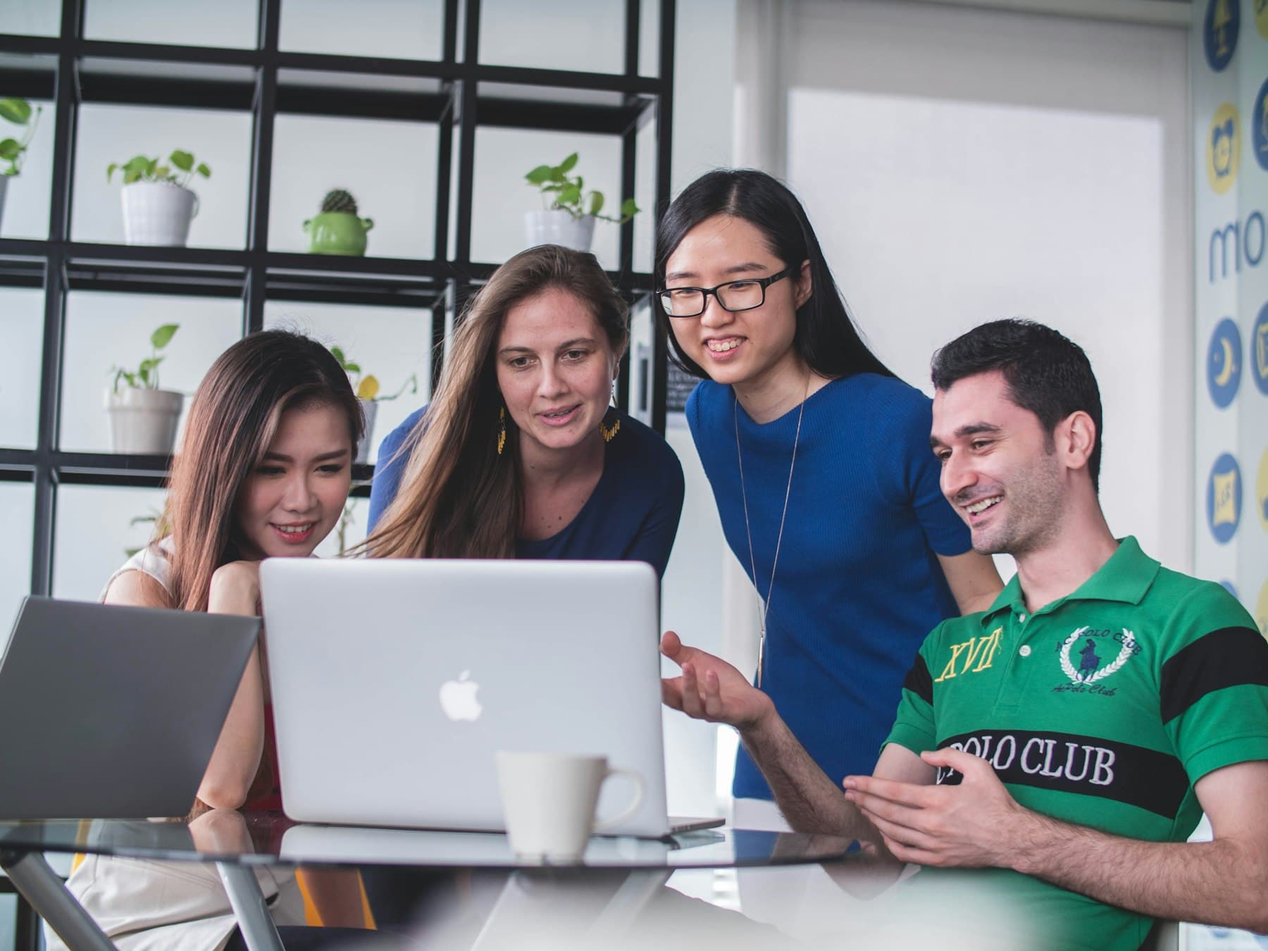 Four colleagues smiling at a laptop screen together
